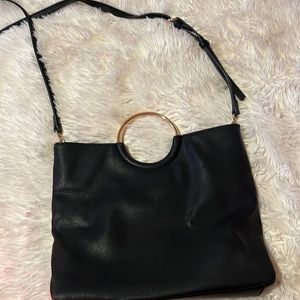 It’s a very simple black bag with a rose gold handle and a black shoulder strap.